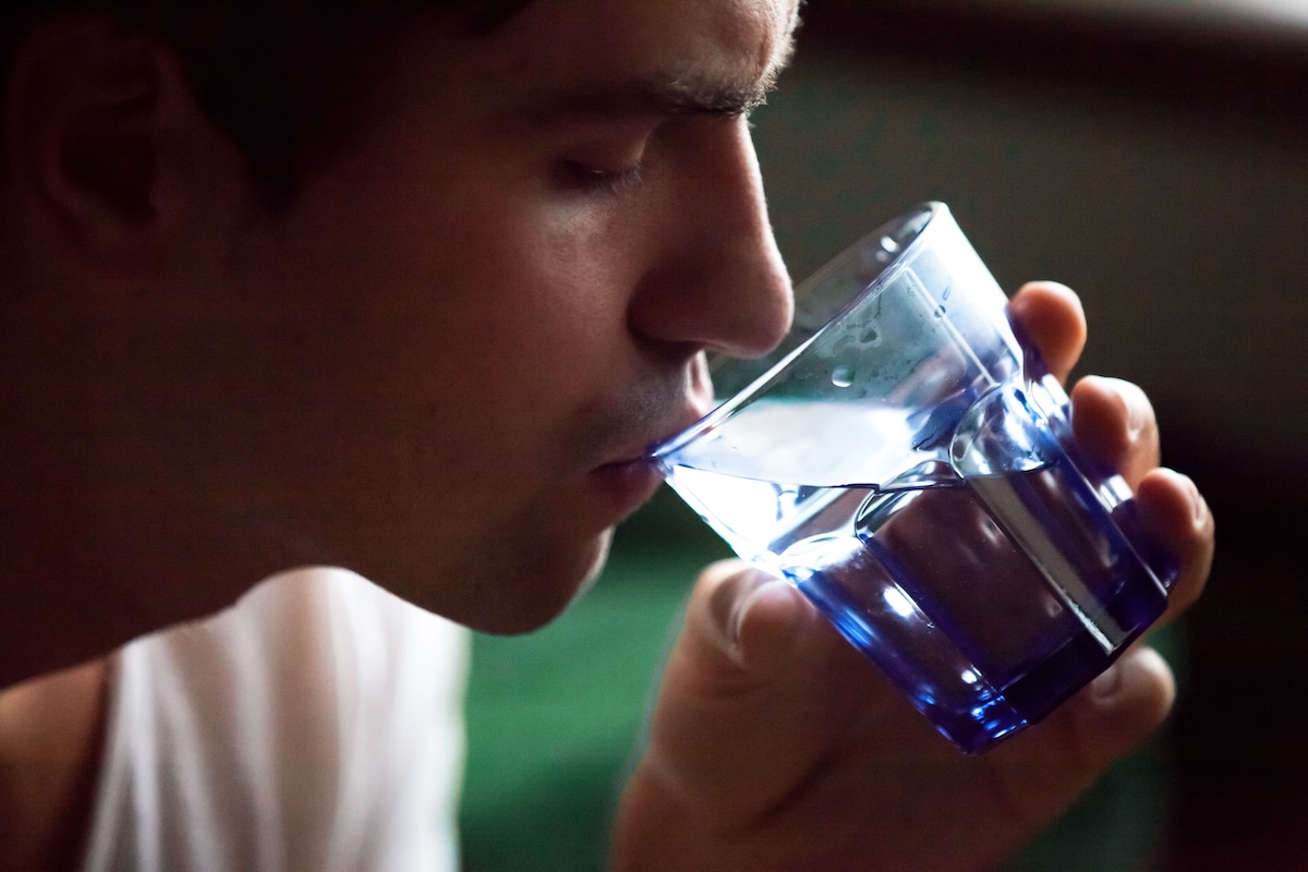 Un homme qui boit un soda sans savoir que sa consommation régulière pourrait être associée à un risque accru de cancer de l’estomac.