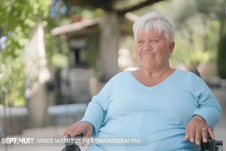 Mimie Mathy, assise dans un fauteuil roulant lors d’une interview accordée à « Sept à Huit » en extérieur.