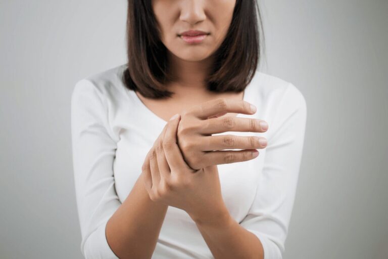 Femme tenant la main en raison d’un engourdissement et de fourmillements, suspectant un syndrome du défilé thoraco-brachial.