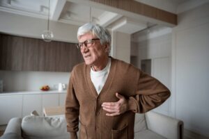 Homme âgé portant une main à sa poitrine, suspectant une fibrillation auriculaire après des palpitations.