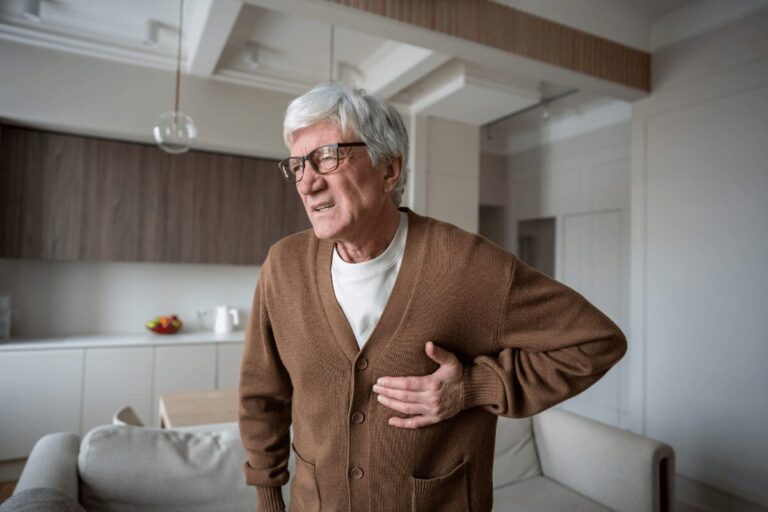 Homme âgé portant une main à sa poitrine, suspectant une fibrillation auriculaire après des palpitations.