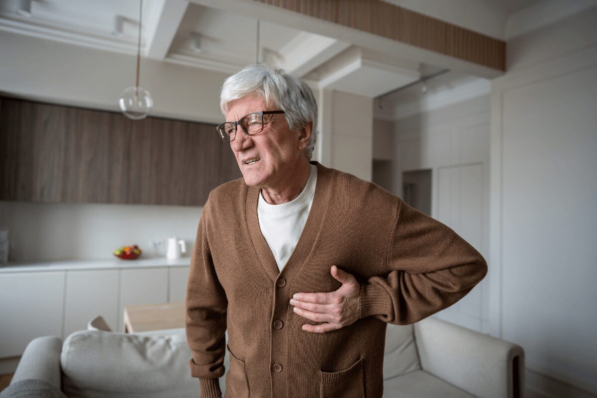 Homme âgé portant une main à sa poitrine, suspectant une fibrillation auriculaire après des palpitations.