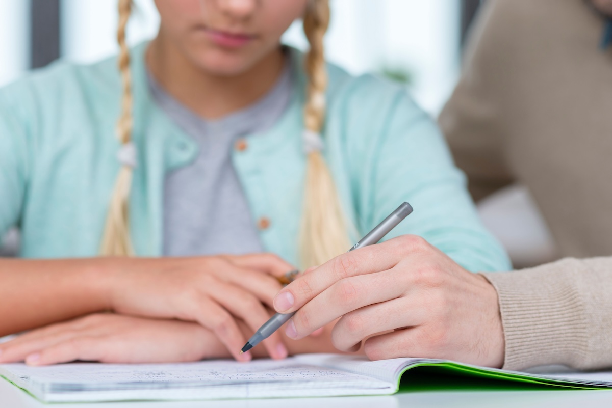 Une élève en plein exercice, accompagnée par un adulte pour progresser et mieux comprendre.