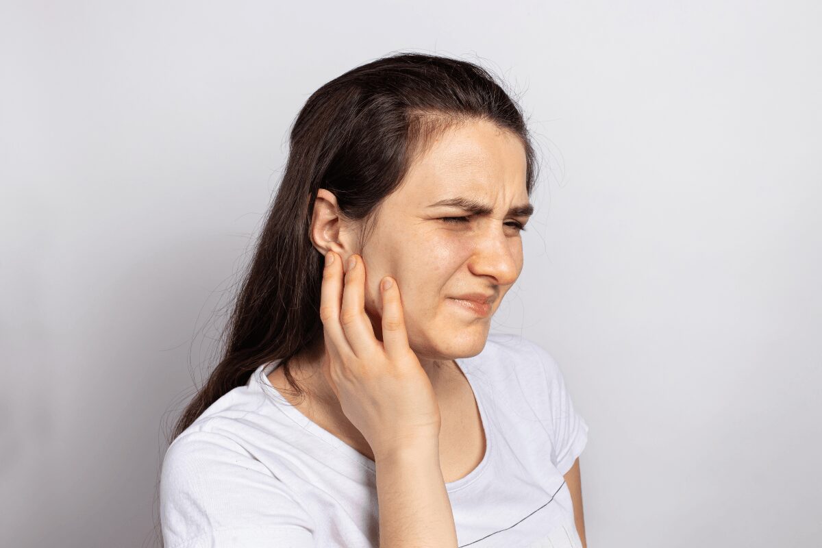 Une femme se tenant l’oreille en raison d’une sensation d’oreille bouchée après un rhume.