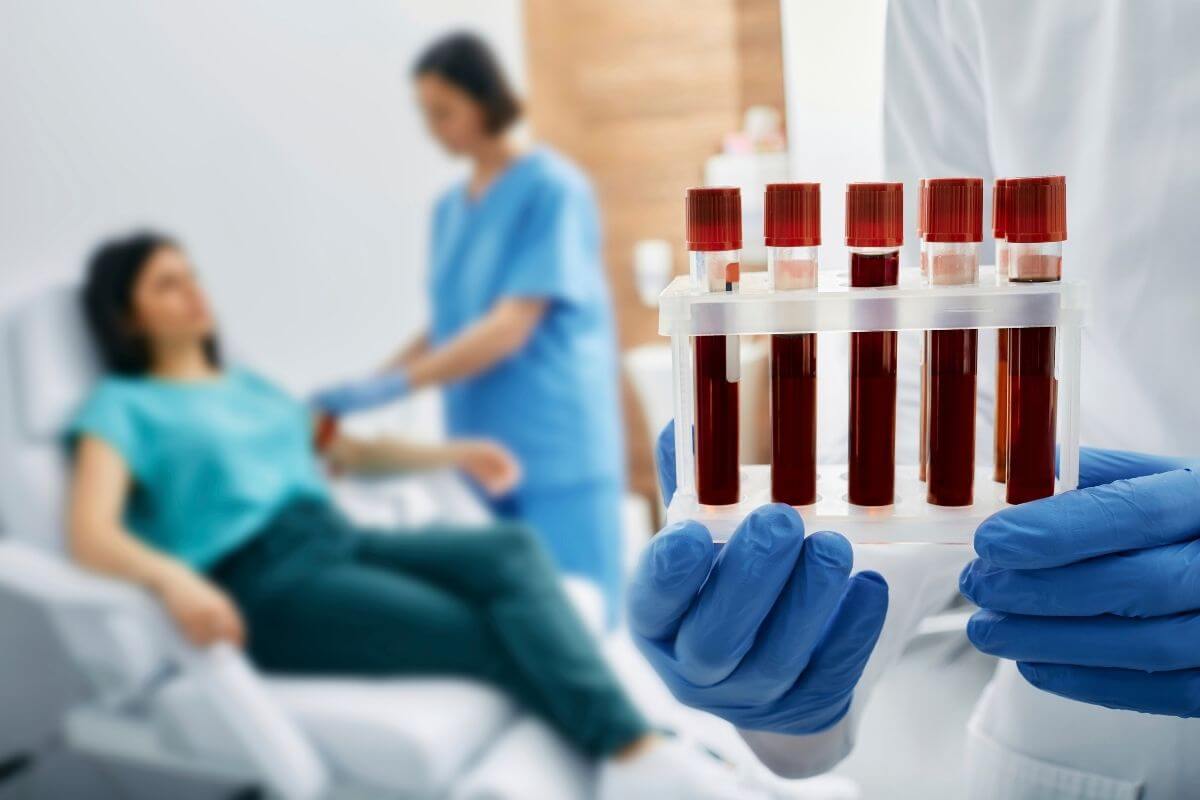 Professionnel de santé tenant plusieurs tubes de sang devant une patiente suspectant un VGM élevé sur sa prise de sang.