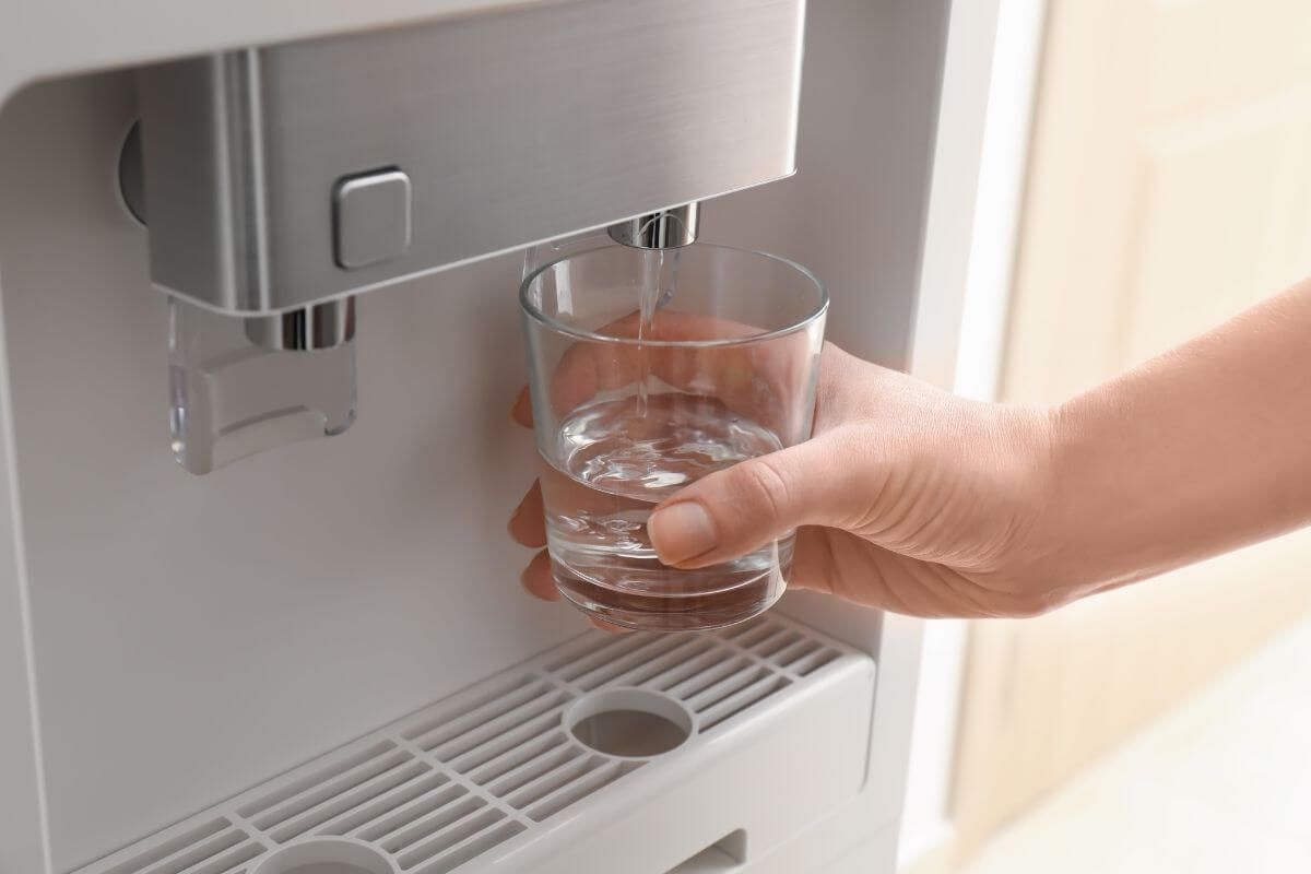 Une personne remplit un verre à une fontaine à eau, pour illustrer le choix entre eau froide, tempérée ou tiède.