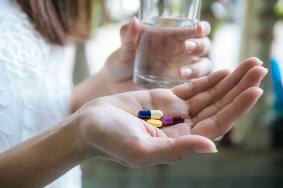 Une femme s’apprête à prendre des médicaments sans ordonnance, sans être certaine de leur efficacité.