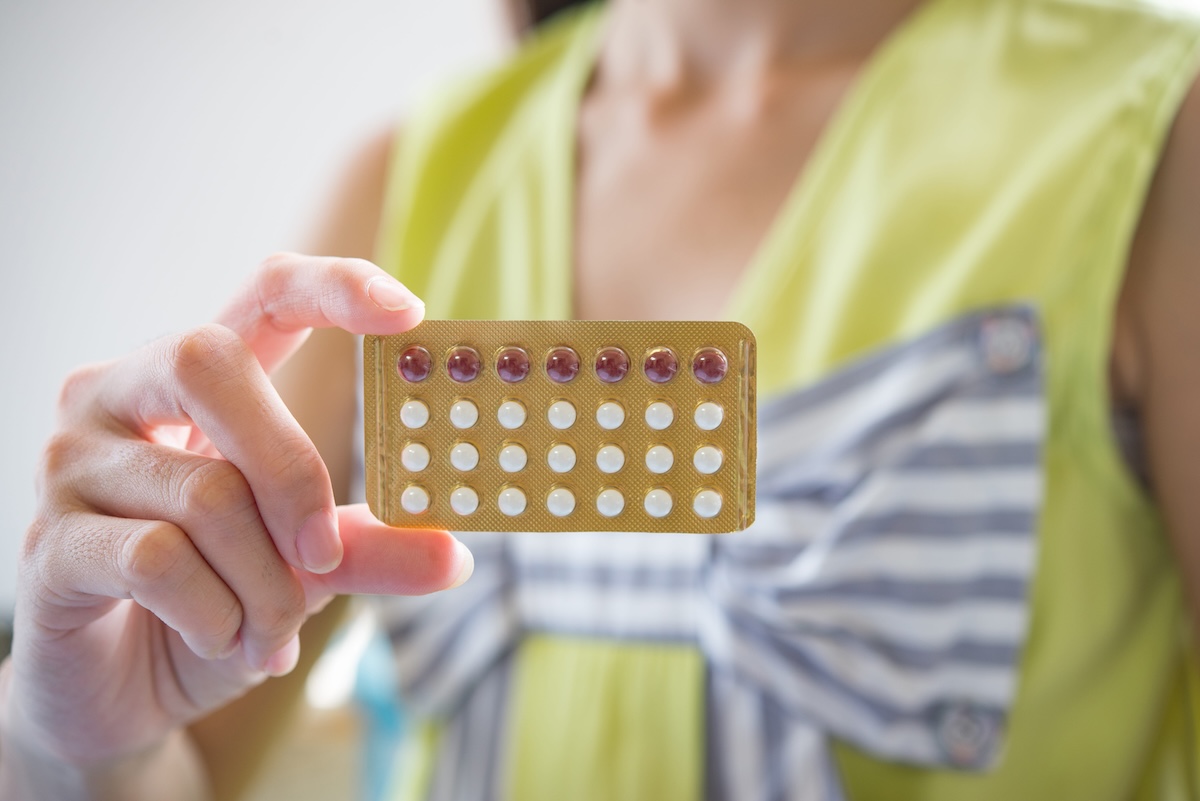 Une femme tient une plaquette de pilules contraceptives, potentiellement en lien avec le risque de méningiome.