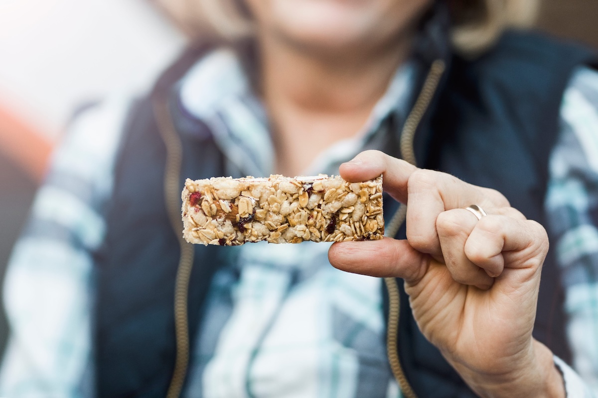 Une femme qui s’apprête à manger une barre de céréales hyperprotéinée.