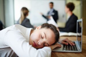 Une femme fatiguée qui s’endort à son poste de travail après son retour de vacances.