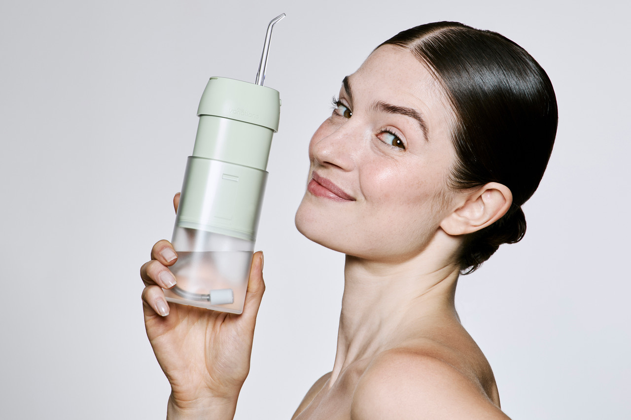 Une femme fière d'utiliser un hydropulseur dentaire pour nettoyer les espaces entre ses dents.