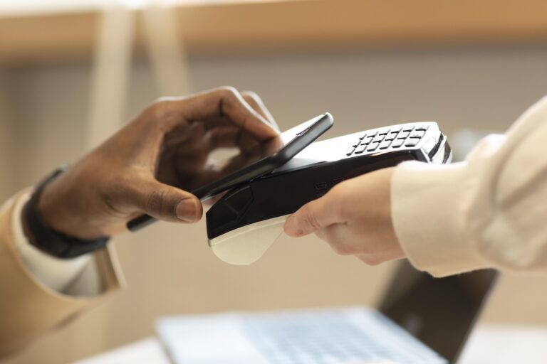Un homme règle des dépassements d’honoraires chez son médecin par paiement sans contact avec son smartphone.