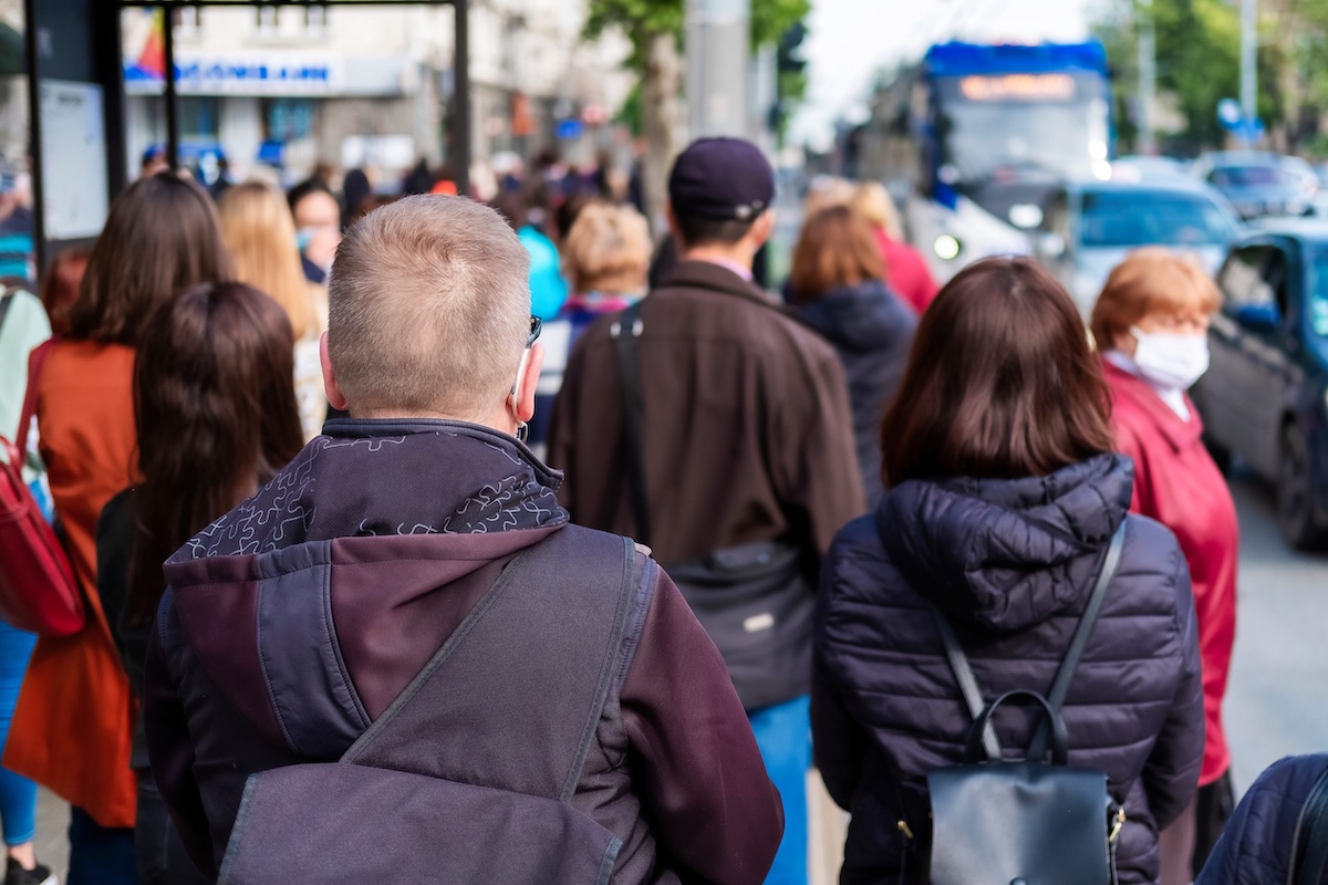 Des passants serrés les uns contre les autres à un arrêt de bus, où la grippe peut se transmettre.