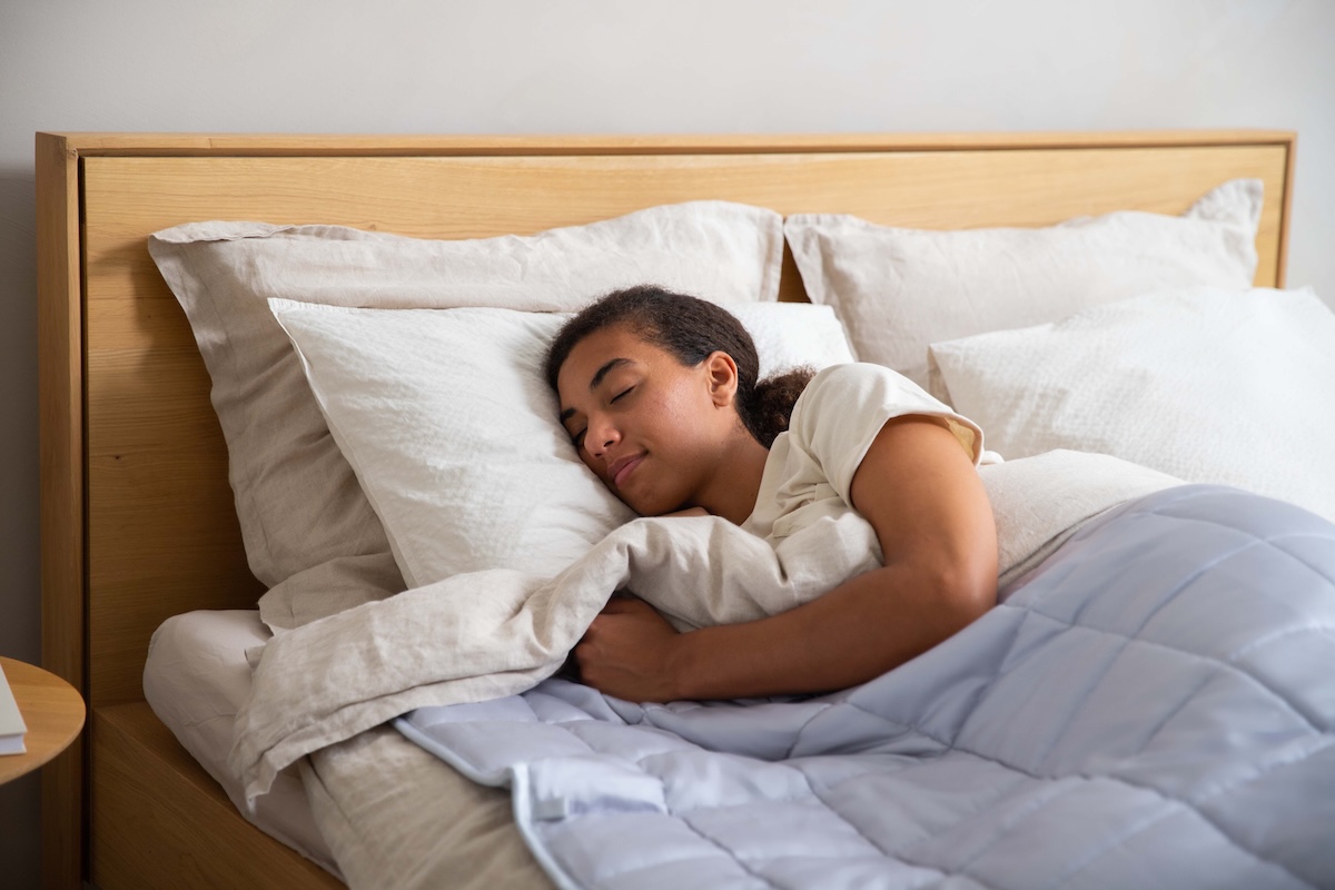 Une jeune femme dort sur le côté dans son lit, une position où le matelas doit notamment bien accompagner les épaules et les hanches.