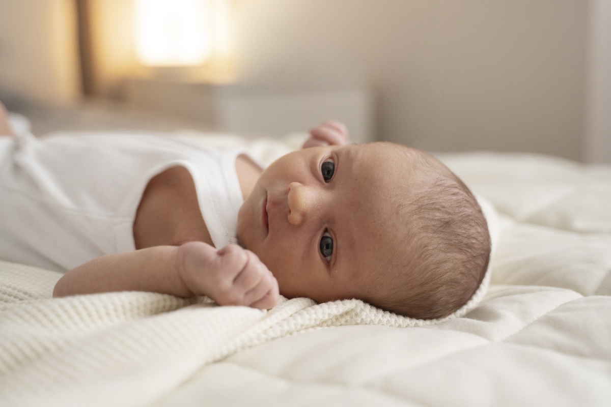 Un bébé allongé sur un lit, dont le développement du cerveau pourrait être affecté par certaines substances chimiques auxquelles sa mère a été exposée pendant la grossesse.