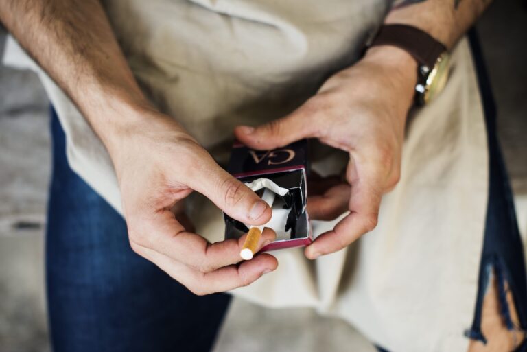 Un homme qui prend une cigarette dans son paquet.
