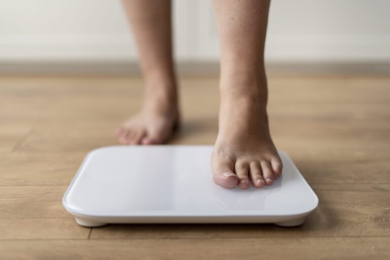 Une personne monte pieds nus sur une balance électronique pour surveiller son poids après la prise de médicament amaigrissant.