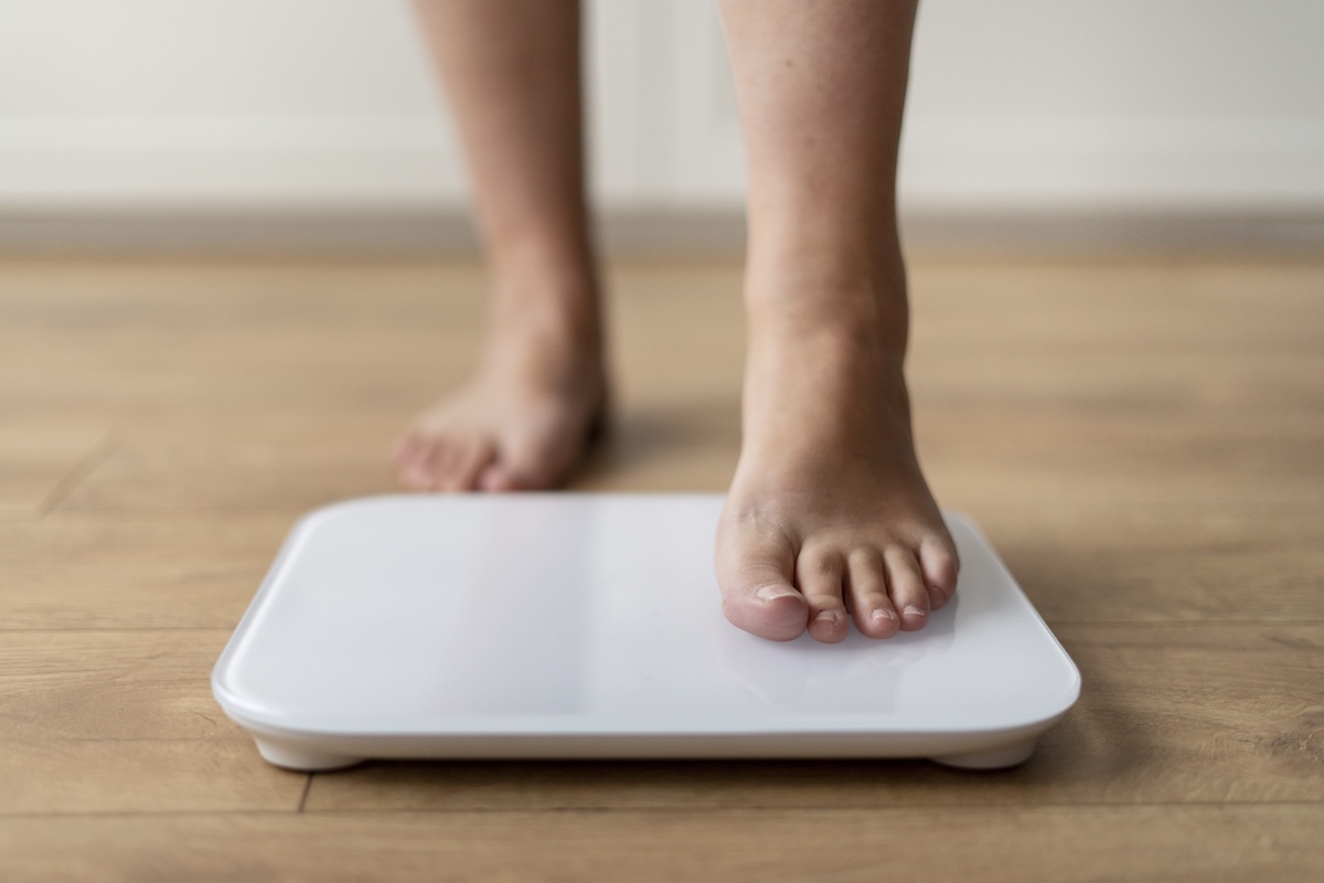 Une personne monte pieds nus sur une balance électronique pour surveiller son poids après la prise de médicament amaigrissant.