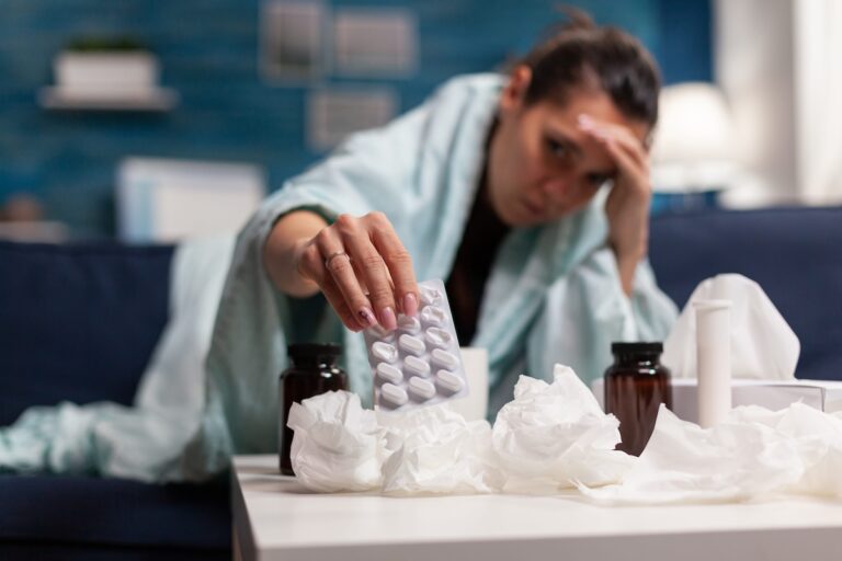 Une femme souffrant d’un rhume hésite entre plusieurs médicaments pour se soigner.