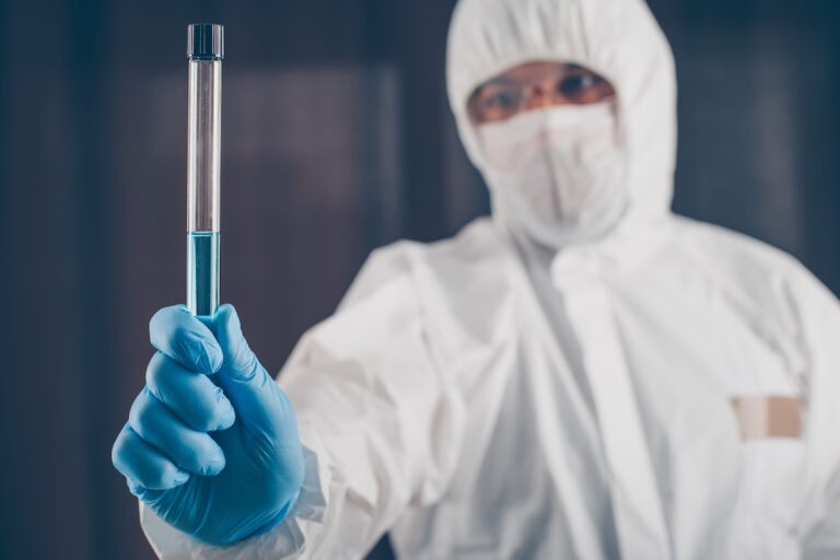 Un professionnel de laboratoire équipé d’une combinaison de protection, d’un masque et de gants manipule un tube contenant la bactérie responsable de la peste.