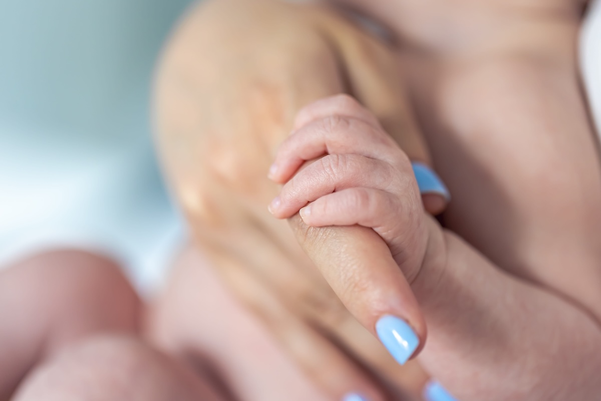 Une maman qui tient la main de son bébé né prématurément.
