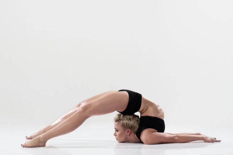 Une jeune femme en réalise une figure de contorsion, les jambes repliées au-dessus de la tête.