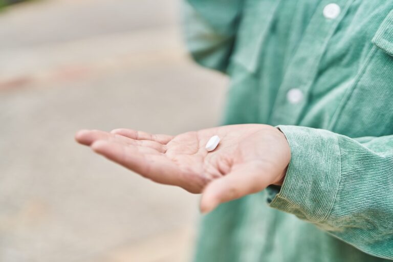 Une personne tient un comprimé de wegovy blanc dans la paume de sa main.